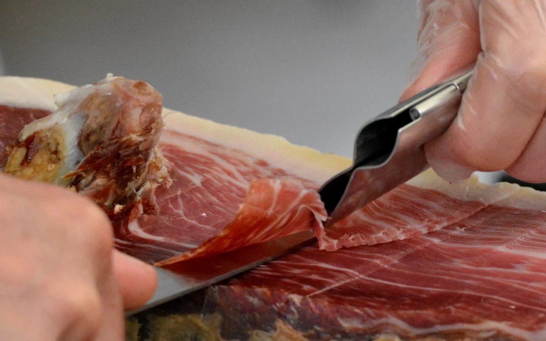 Persona cortando jamón